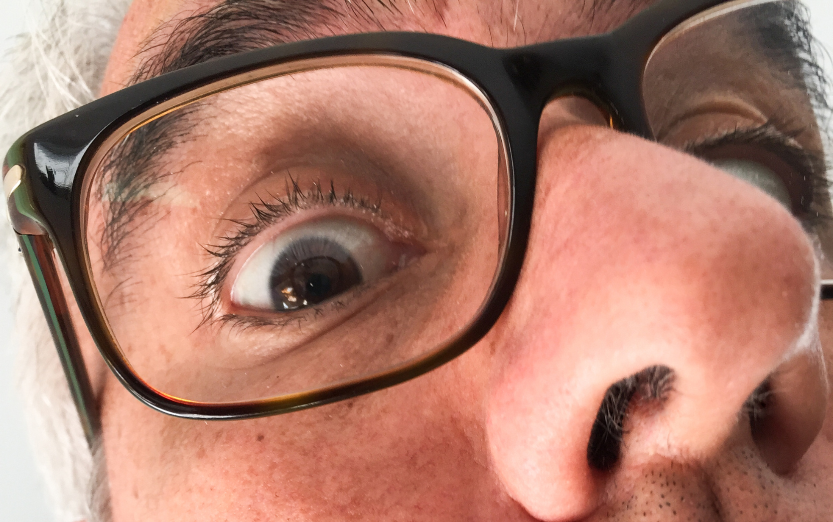 Gros plan en contre plongée d'un oeil qui regarde l'objectif à travers des lunettes