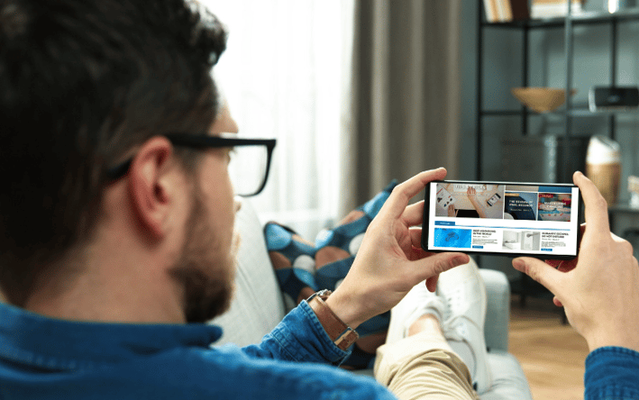 Homme vu de dos, en train de consulter un article de blog sur son smartphone